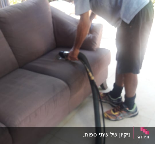 אדם מנקה ספה עם שואב אבק חזק